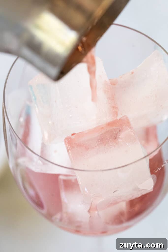 pouring a cocktail into a large wine glass
