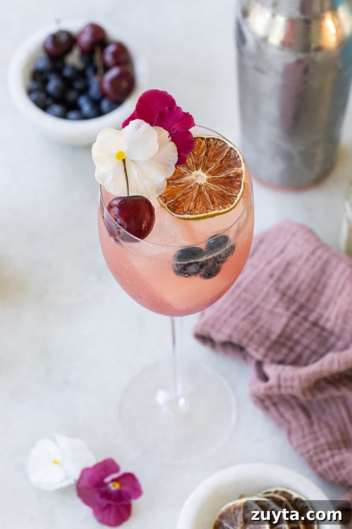 Beautiful gin spritz in a wine glass with cherries and edible flowers.