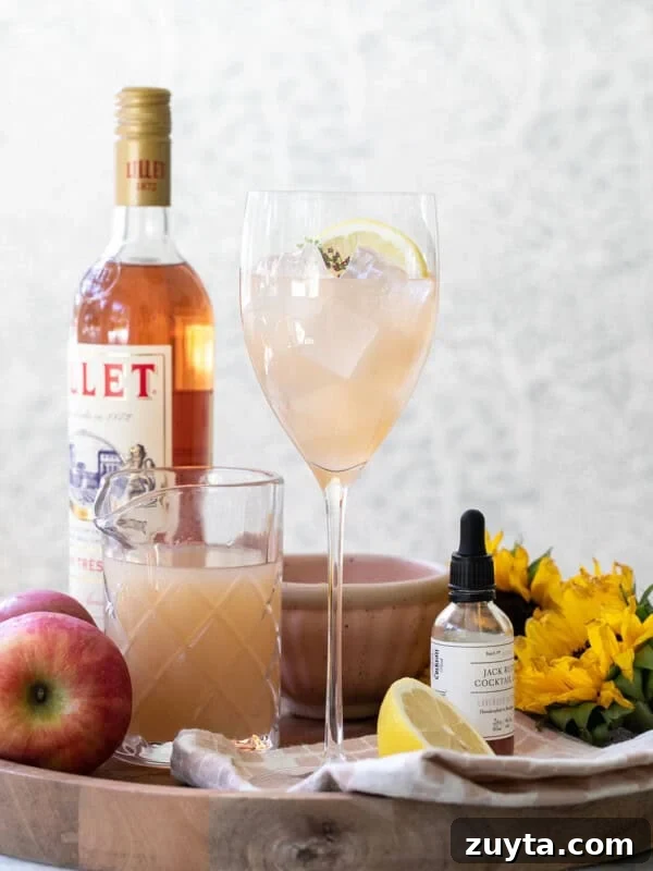 apple cider spritz on a wood platter with a bottle of Lillet.