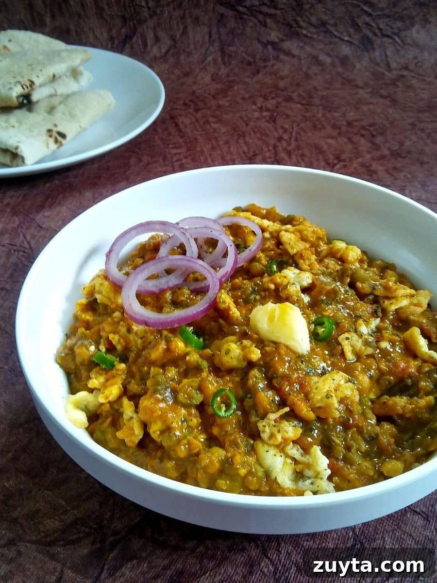 Authentic Bengali Egg Tadka Recipe 2 Egg Tadka served in a bowl topped with onion rings.