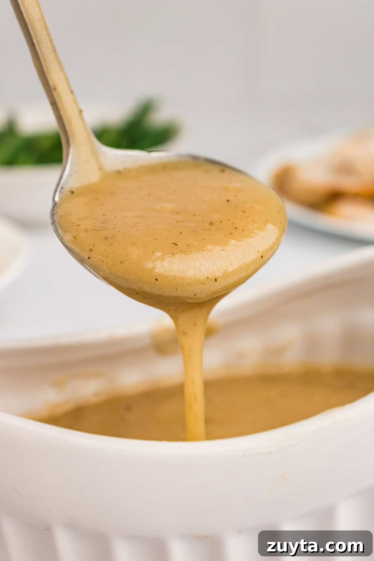 How to Make Turkey Gravy Without Drippings 2 Turkey gravy without drippings in gravy ladle dripping into gravy boat below it.