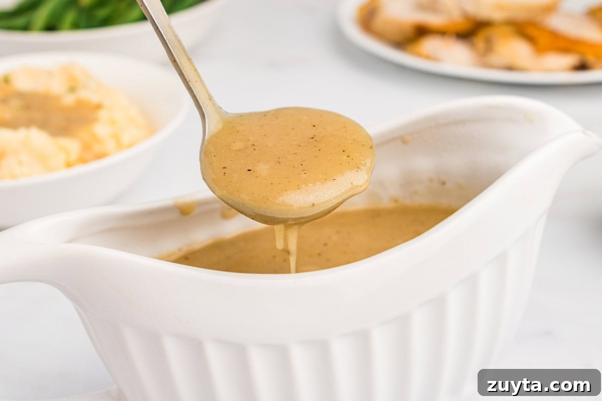 How to Make Turkey Gravy Without Drippings 12 Easy homemade turkey gravy in gravy boat and spooned into a ladle. Roast turkey, mashed potatoes, and green beans are in the backgound.