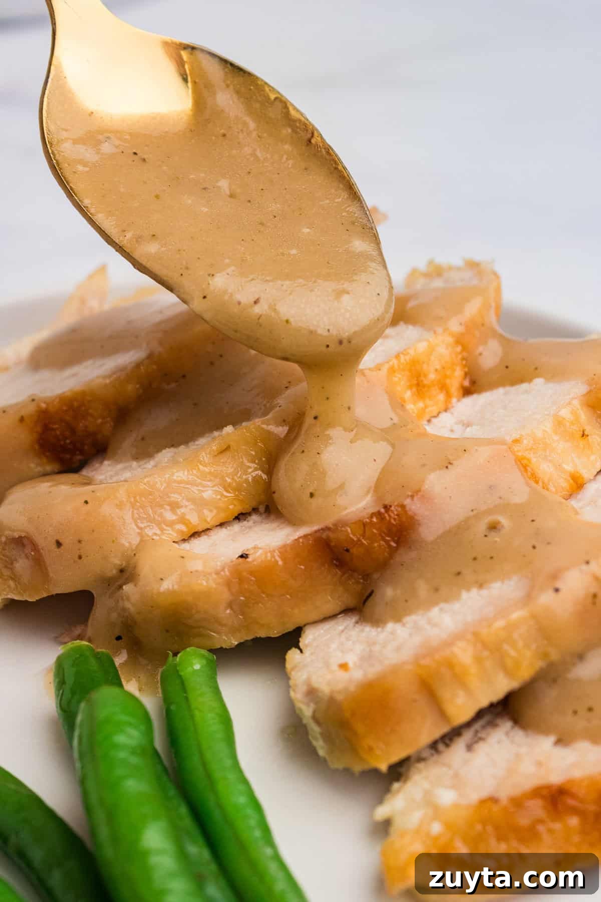 How to Make Turkey Gravy Without Drippings 3 Thanksgiving gravy being drizzles over sliced toast turkey.