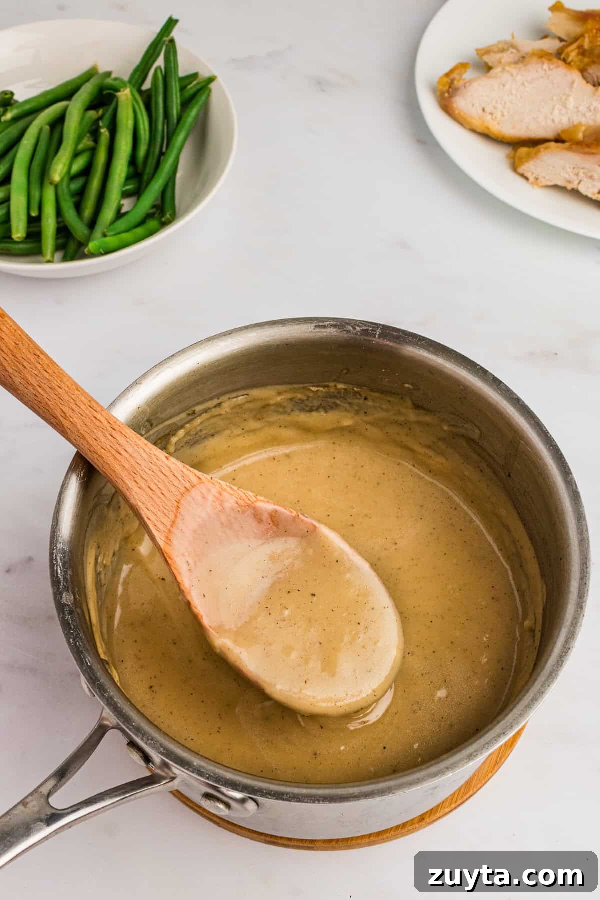 How to Make Turkey Gravy Without Drippings 8 Pot of thick homemade gravy beside turkey and green beans.
