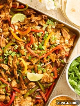 Sheet pan chicken fajitas topped with lime wedges.