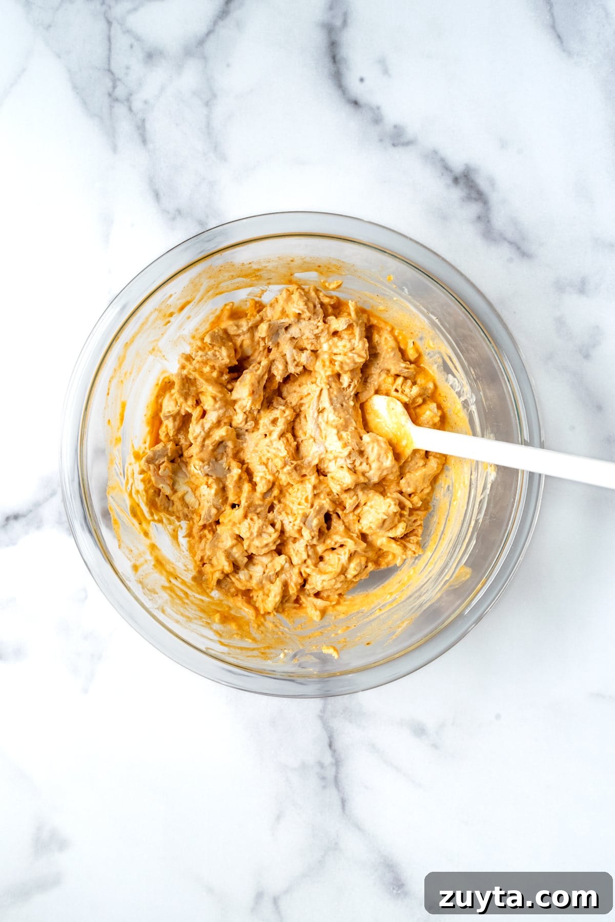 Creamy Buffalo Chicken Dip with Greek Yogurt 5 Mixed Buffalo Chicken Dip with Greek Yogurt in a Glass Mixing Bowl with a spoon.