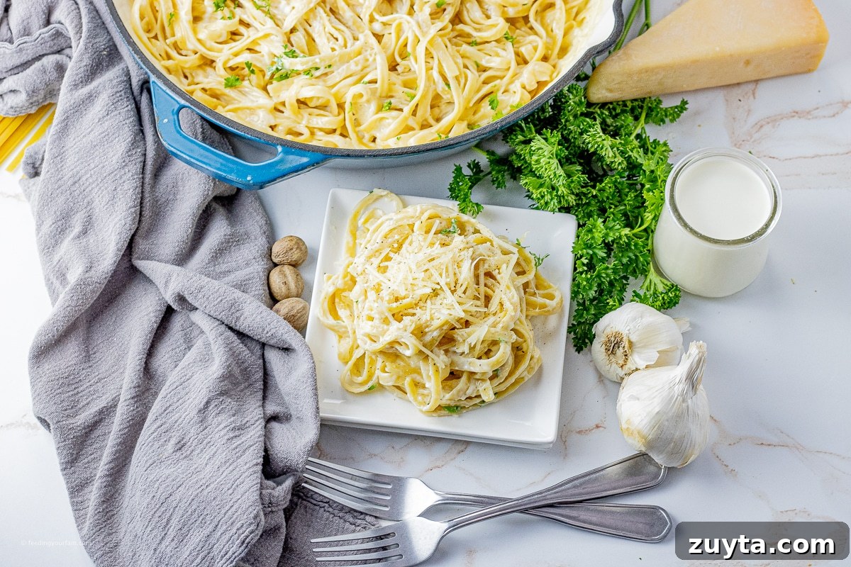 5-Ingredient Creamy Homemade Alfredo Sauce 3 fettucinne noodles in alfredo sauce in a big skillet with some on a small white plate