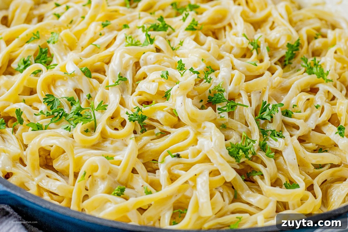 5-Ingredient Creamy Homemade Alfredo Sauce 7 fettucine noodles covered in alfredo sauce and parsley in a large skillet