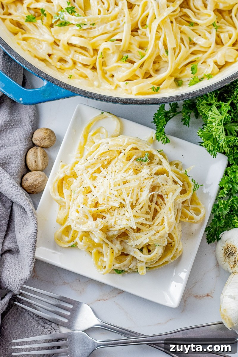 5-Ingredient Creamy Homemade Alfredo Sauce 8 fettucine noodles covered in alfredo sauce in a pile on a white plate