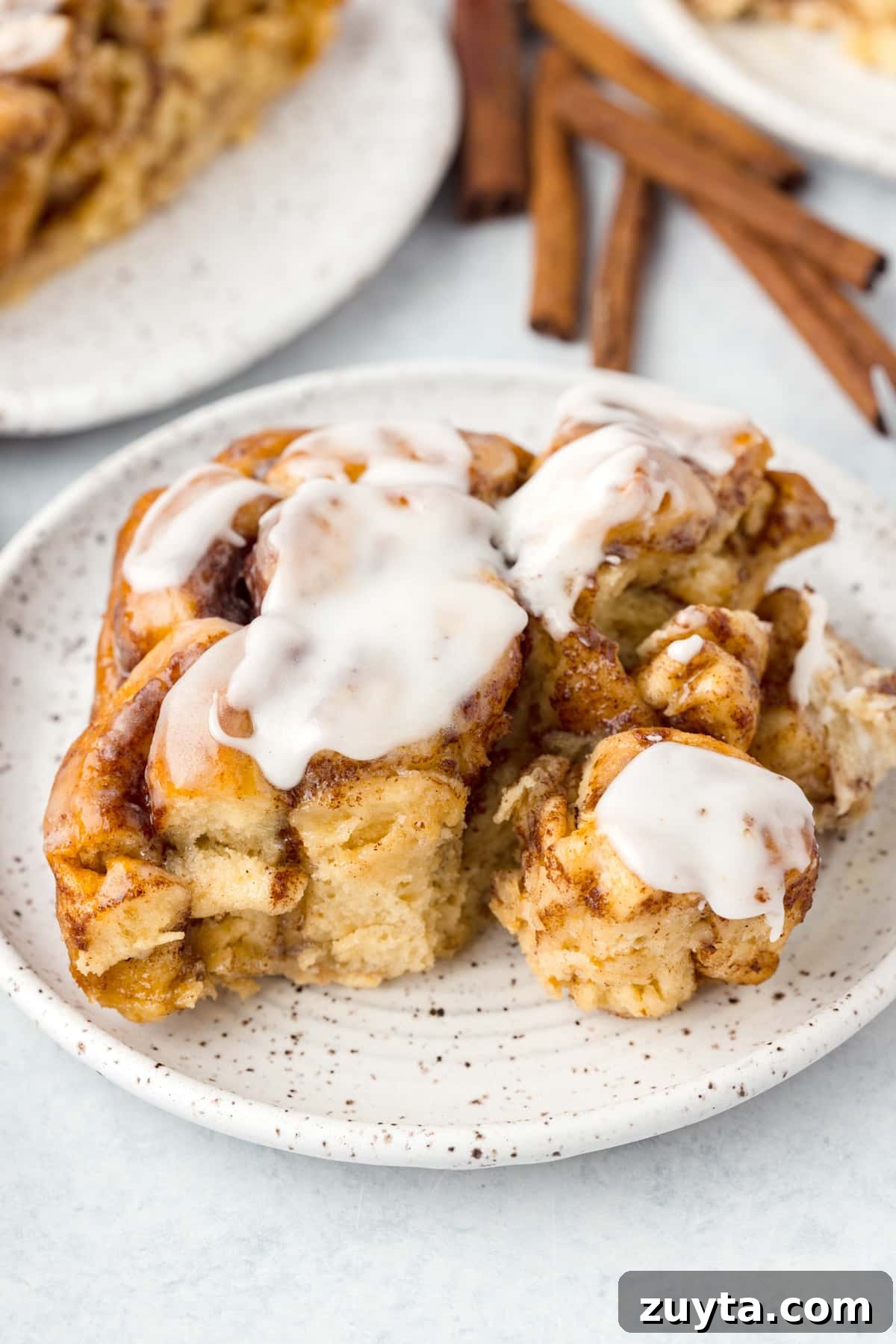 Cinnamon Roll Casserole Recipe with Cream Cheese Glaze 2 A cinnamon roll on a plate, topped with icing.