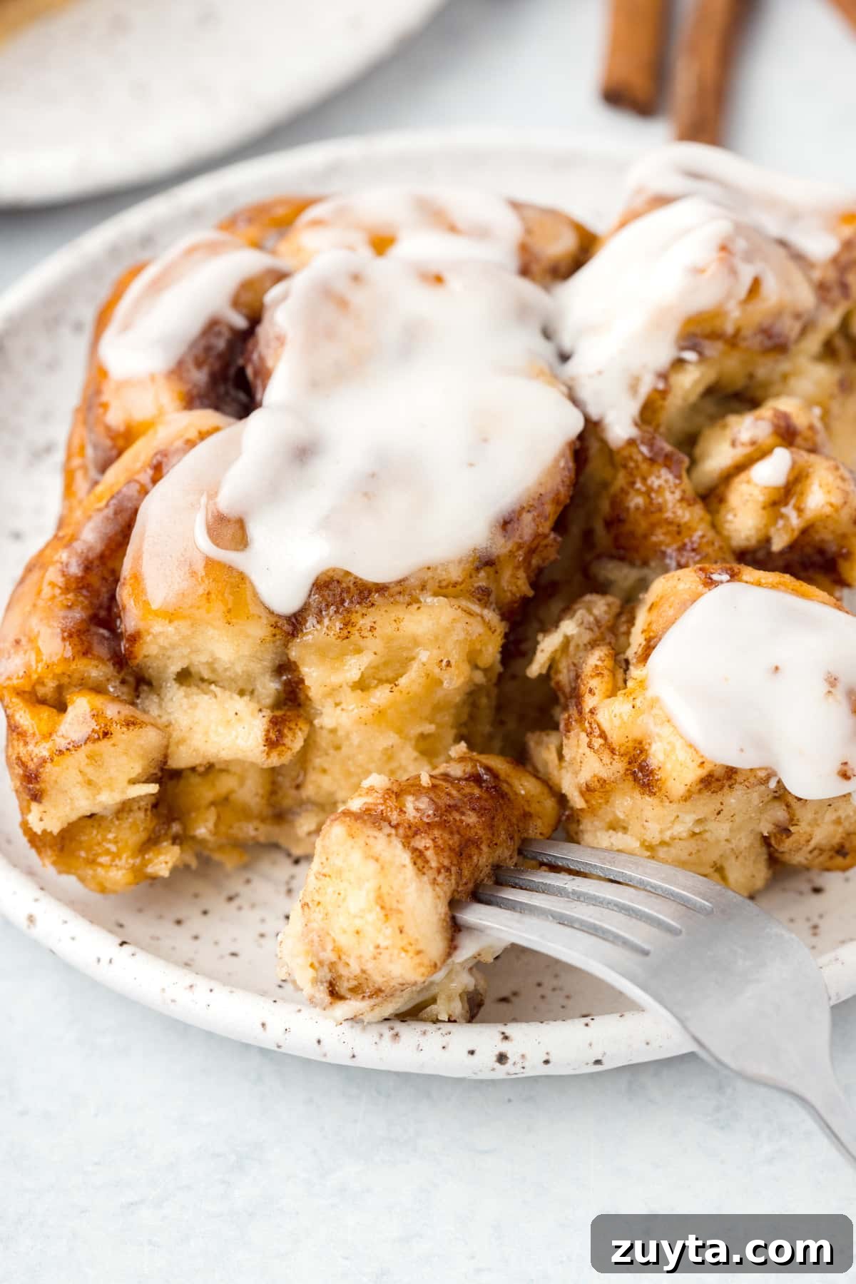 Cinnamon Roll Casserole Recipe with Cream Cheese Glaze 11 A fork taking a portion from a cinnamon roll.