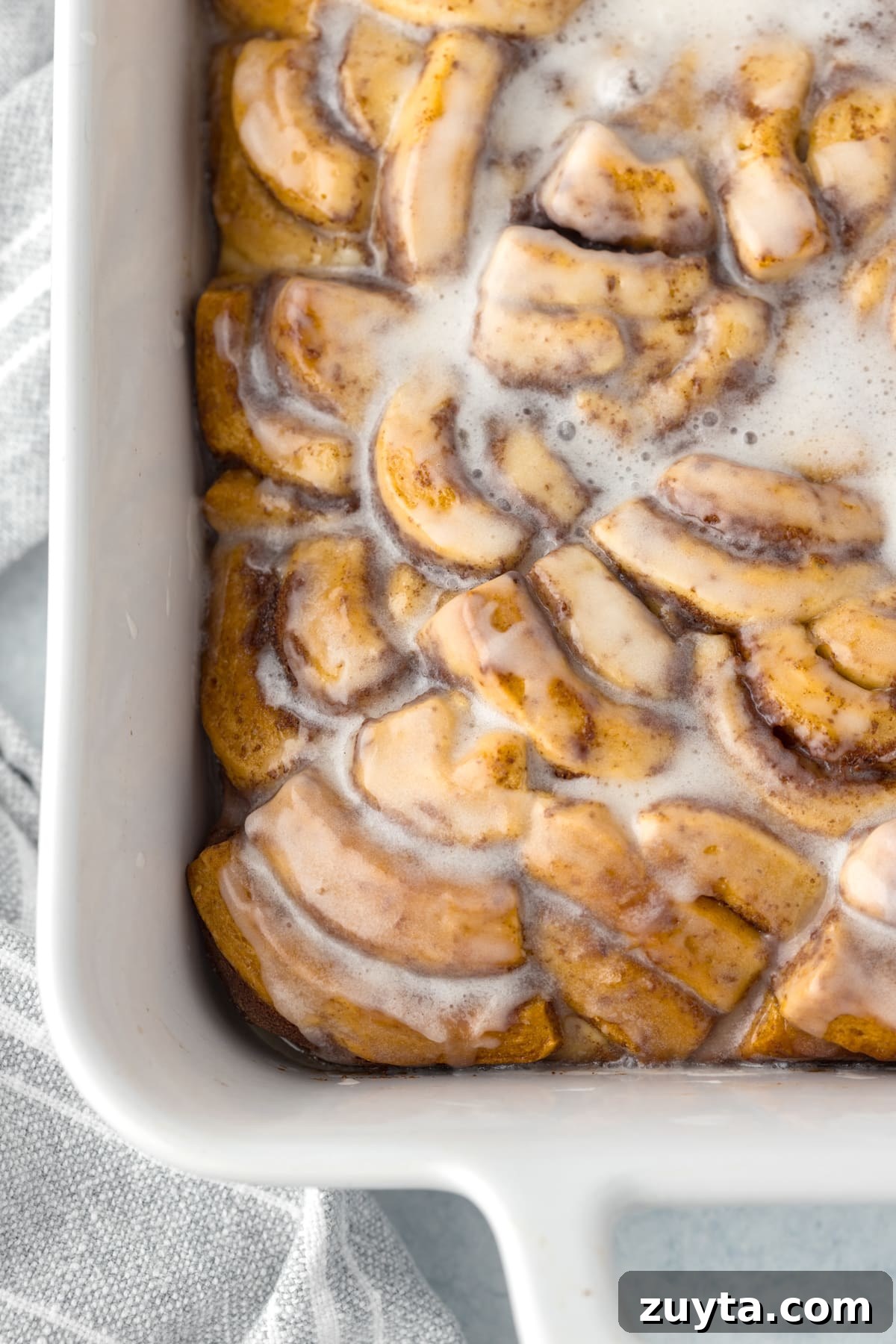 Cinnamon Roll Casserole Recipe with Cream Cheese Glaze 12 A baking dish filled with cinnamon roll pieces, baked and topped with icing.