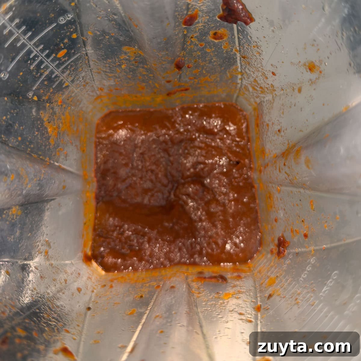 Making chili paste in a blender with soaked dried chilies and soaking water.