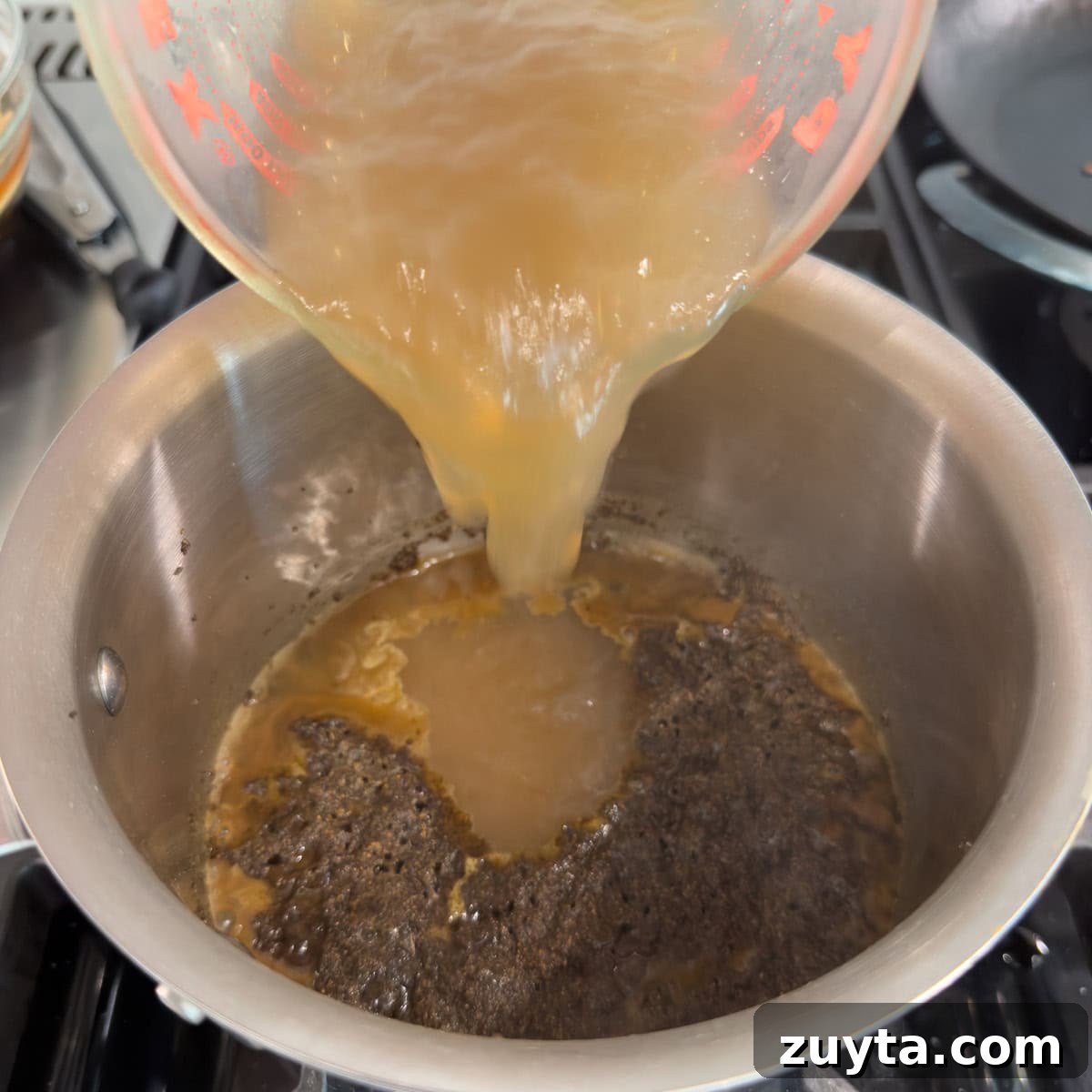 Adding broth to a pot of spices and roux to make sauce.