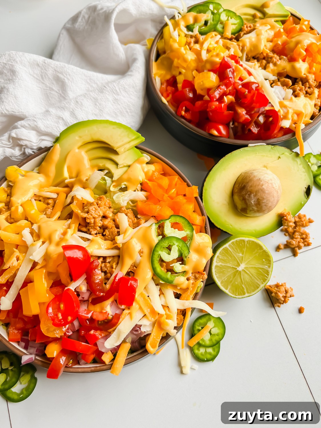 loaded taco salad bowl garnished with jalapenos, avocado, and cheese.