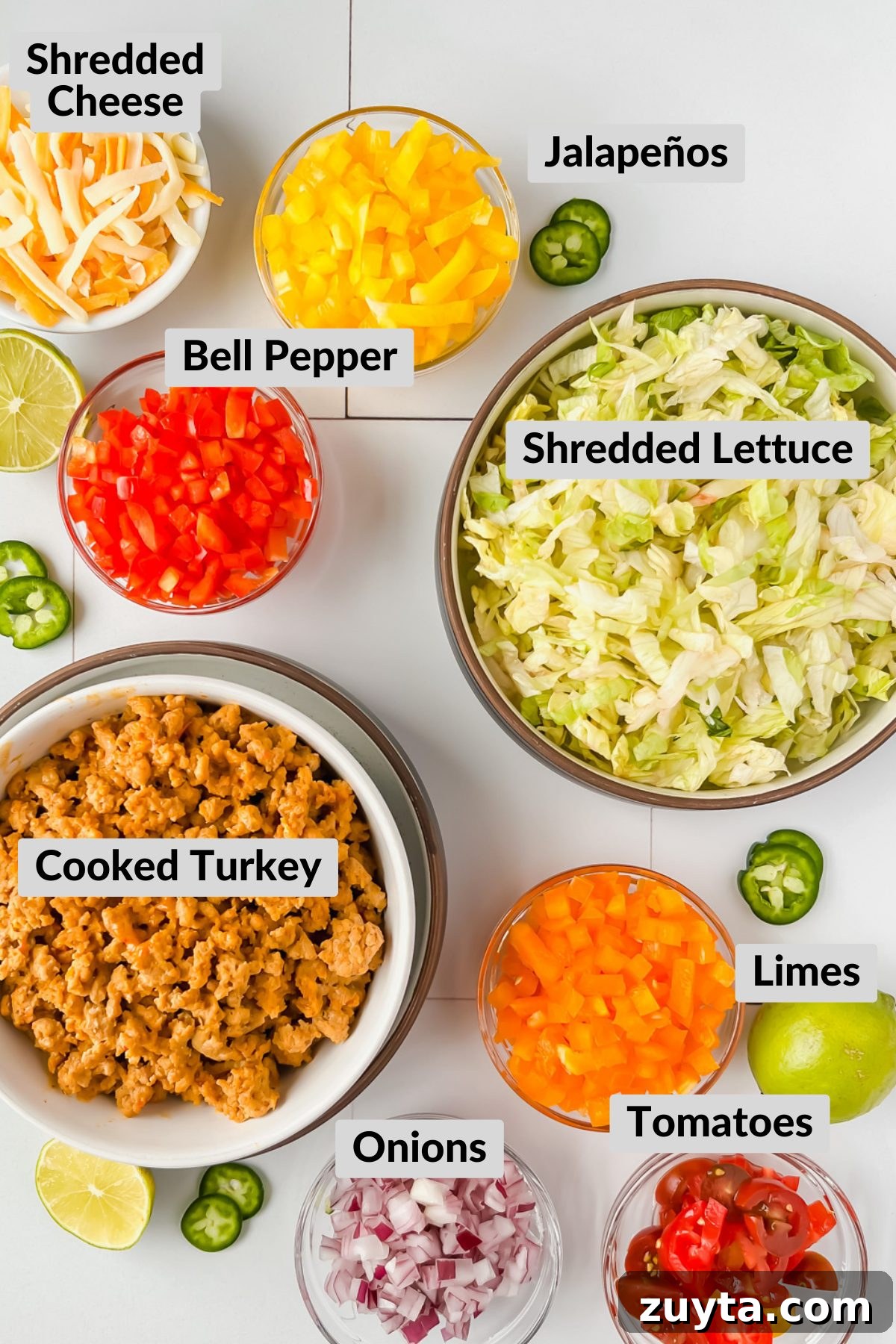 overhead shot of all taco salad bowl ingredients in respective bowls on white background.