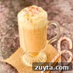 Toasted white chocolate mocha with caramel drizzle and sugar sprinkles, with two candy canes beside it.