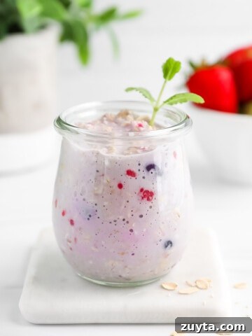 A glass jar filled with berry overnight oats.
