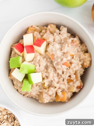 Cooked apples in oatmeal topped with fresh apples.
