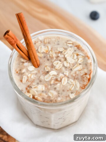 A jar of overnight oats and cinnamon sticks in the oats.