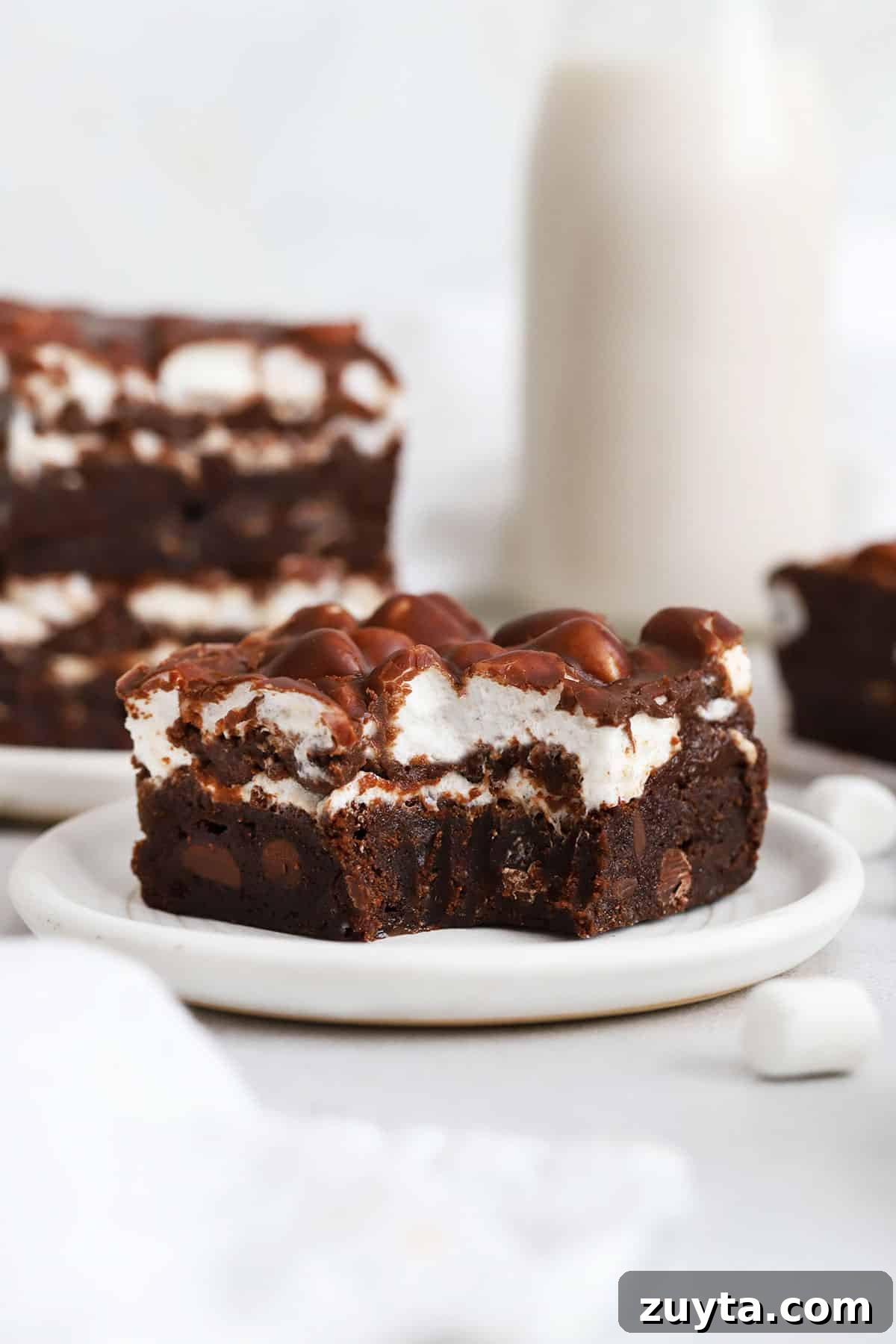 Fudgy Gluten-Free Marshmallow Brownies Recipe 7 a gluten-free marshmallow brownie on a plate with a bite taken out of it