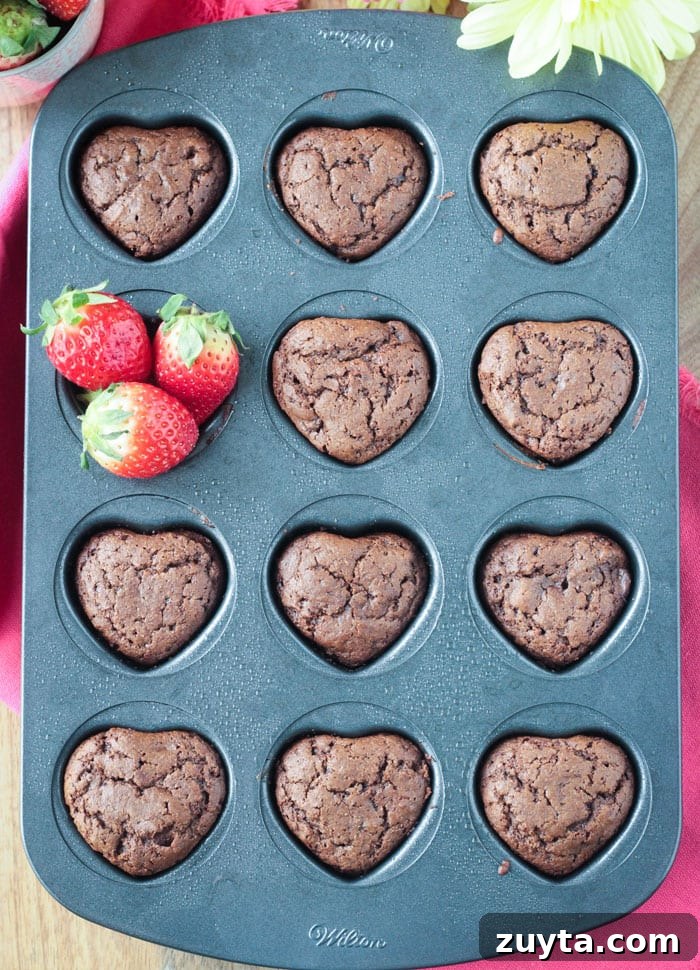 Tahini Chocolate Chip Cupcakes - These adorable little mini cupcakes are perfect for Valentine's Day. Treat your sweetie...or your kids...or yourself...to some chocolate indulgence made healthier with no dairy, no eggs, no oil, and no refined sugar. Heart shaped cupcake pan filled with chocolate cupcakes. One cavity has fresh strawberries in it instead of a cupcake.