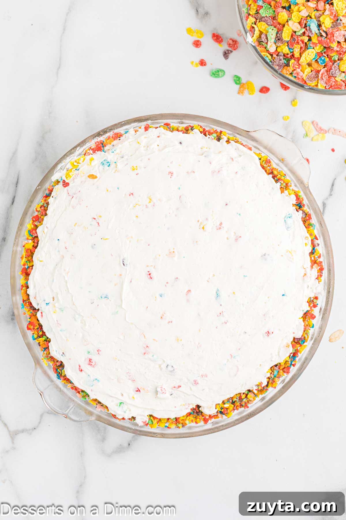 Fruity Pebbles Cheesecake Recipe with Rainbow Cereal Topping 8 Mixture spread into pan over crust.