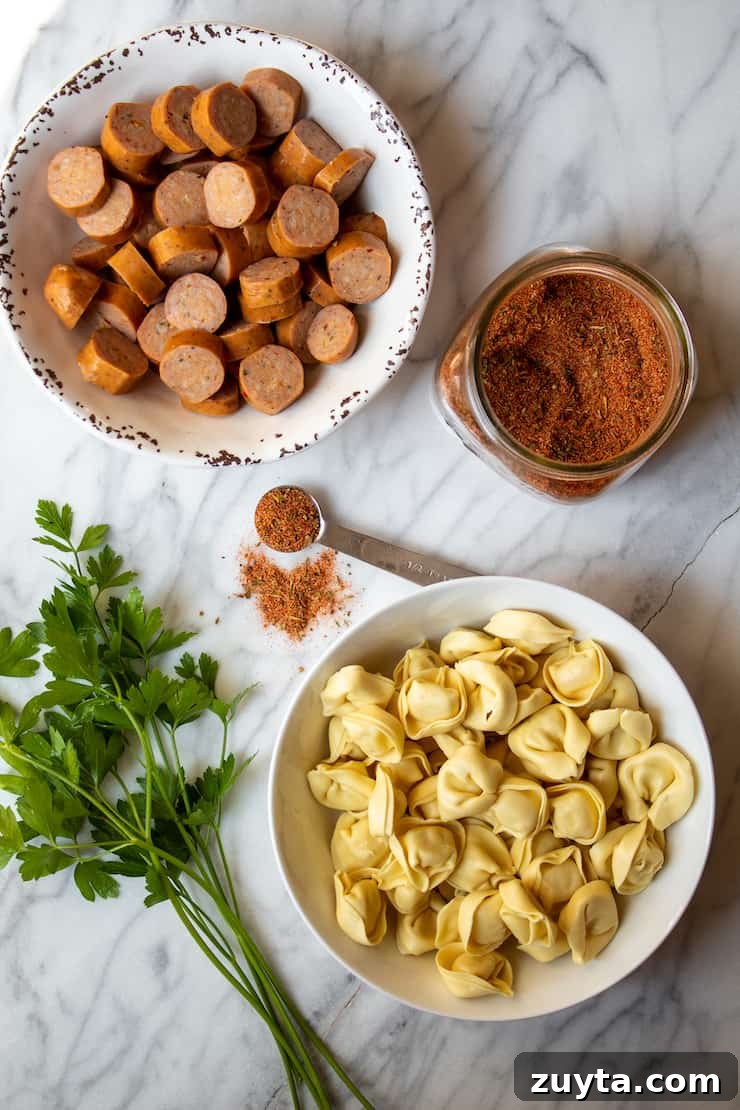 Creamy Cajun Tortellini Soup Recipe 4 Close up of tortellini, sausage and homemade Cajun seasoning on marble board.