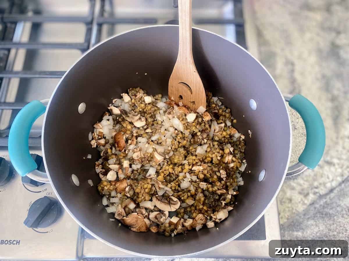Hearty Vegan Goulash Recipe: Hungarian-Style Stew 5 cooking the mushrooms and lentils with the onions and garlic in the pot on the stove
