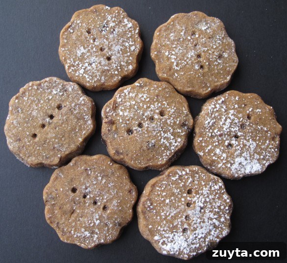 Seven Espresso Chocolate Shortbread Cookies dusted in powdered sugar on a black background.
